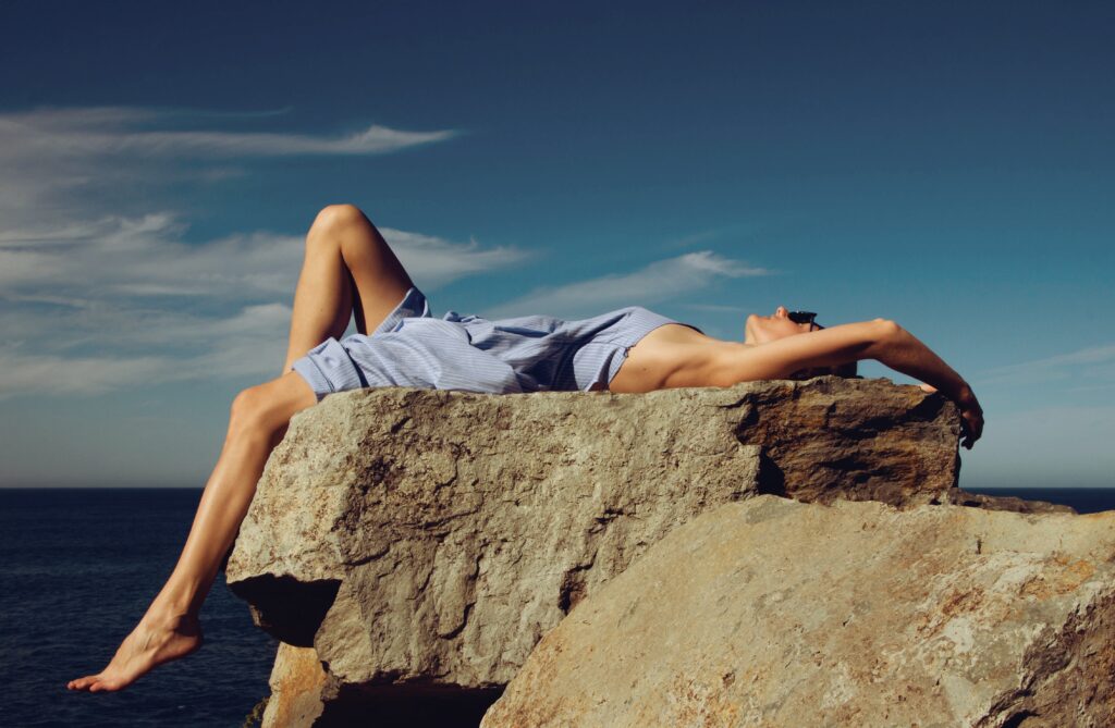 Woman laying in the sun tanning on a rock
